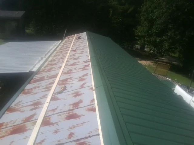 Old rusted panels beside newly installed green metal roofing — Wind Damage Roof Repair by Roofing Brothers in Du Pont