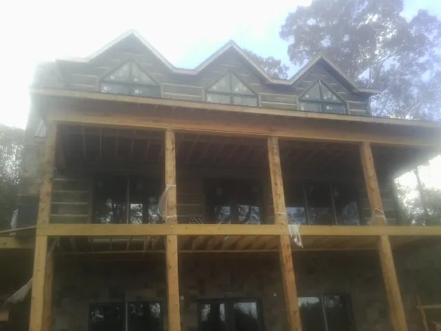 Dormers and porch framing on a large log home under construction — Roof Coating work by our crew in Du Pont