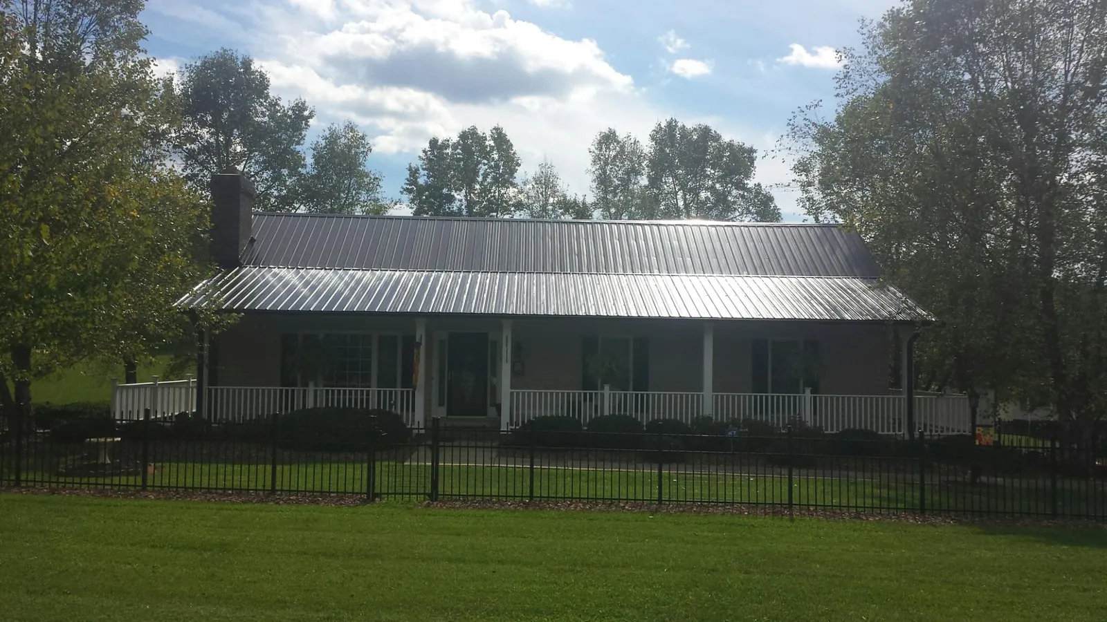 Gray metal roof on a brick ranch with a full width front porch — Gutter Guard Installation work by our crew in Du Pont