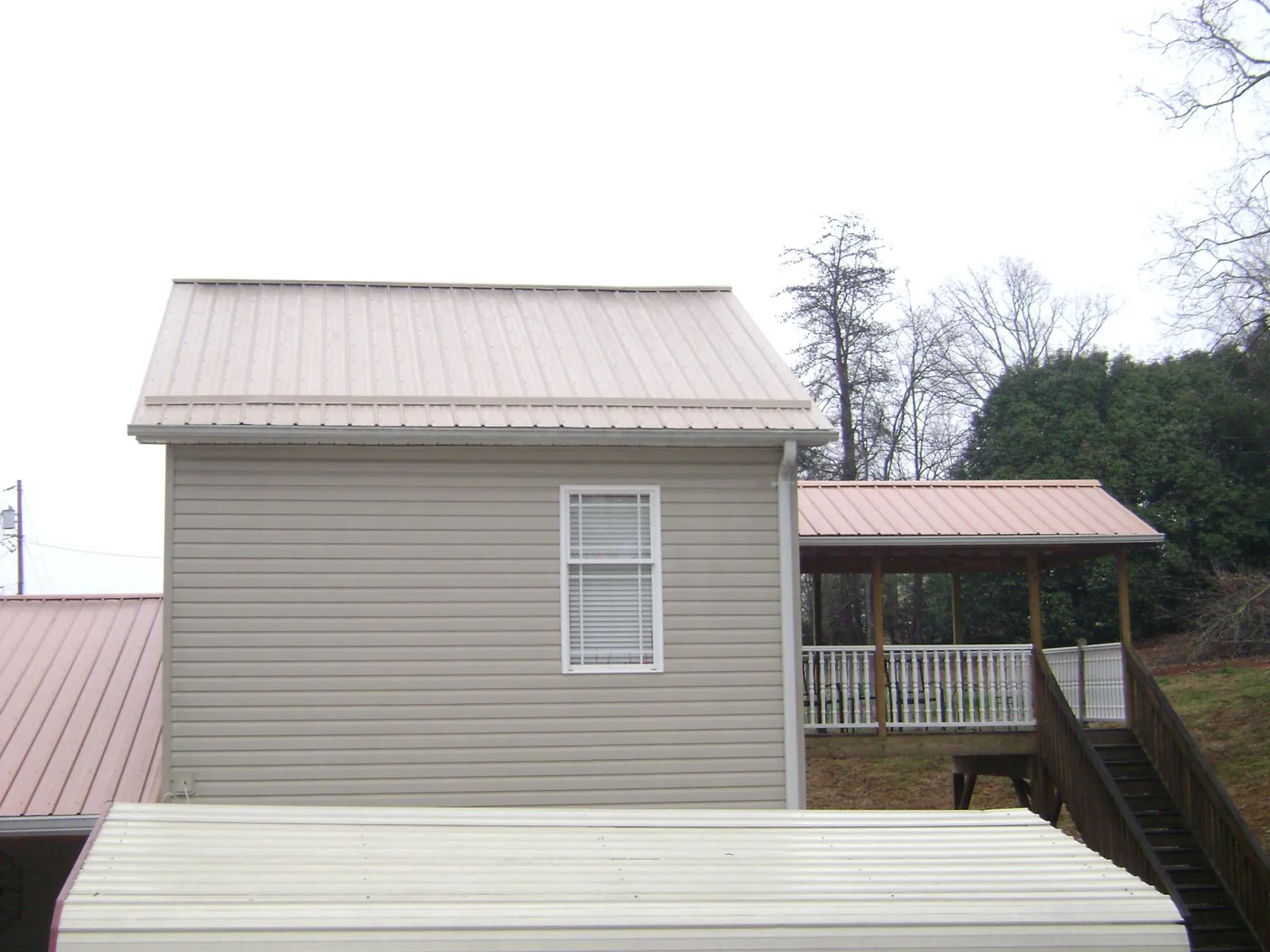 Tan metal roofs on a two story addition and attached porch, from a Roof Replacement job in Du Pont