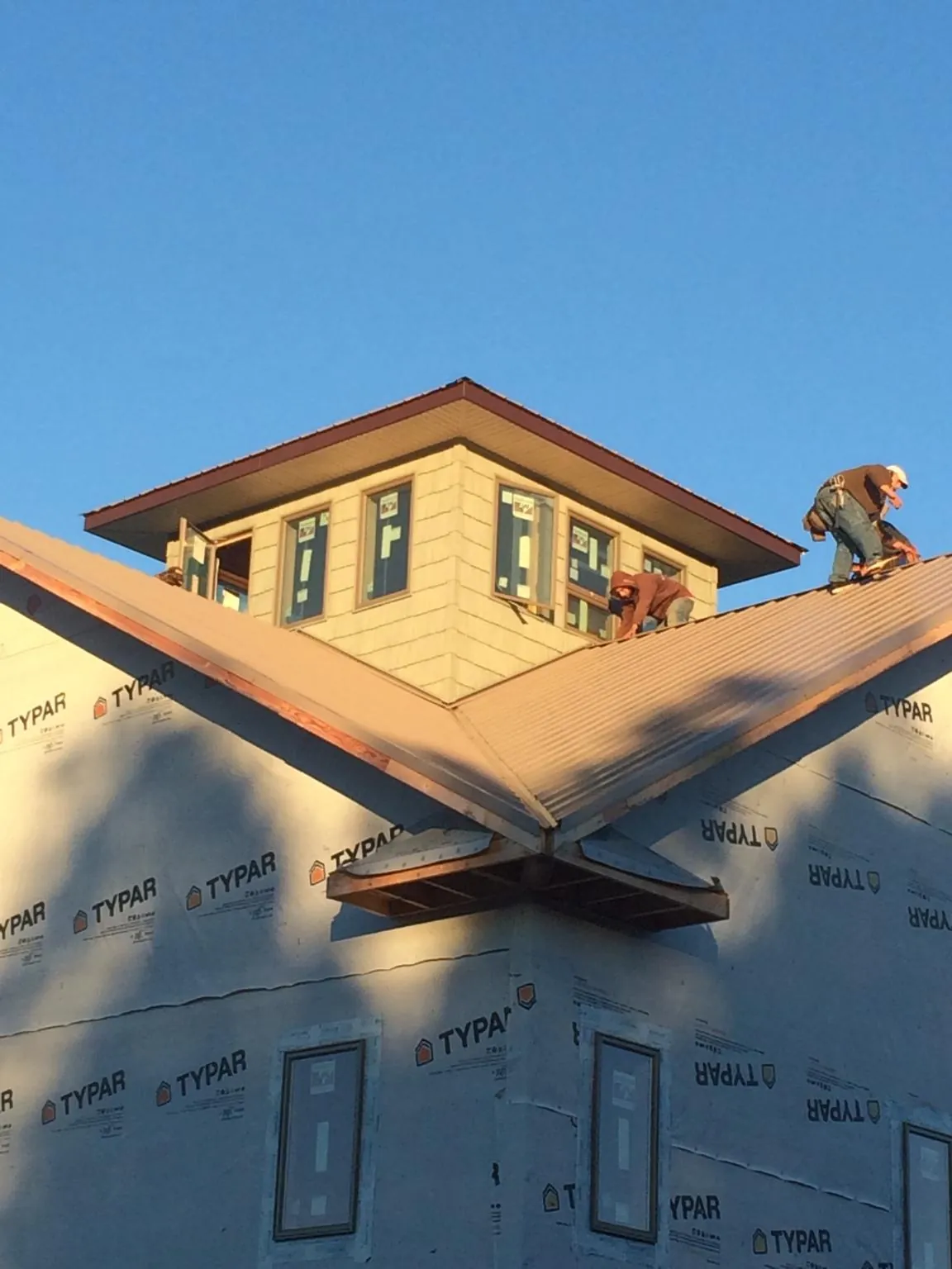Roofers working around a rooftop cupola on a new metal roof at sunset — Roof Waterproofing in Du Pont by Roofing Brothers